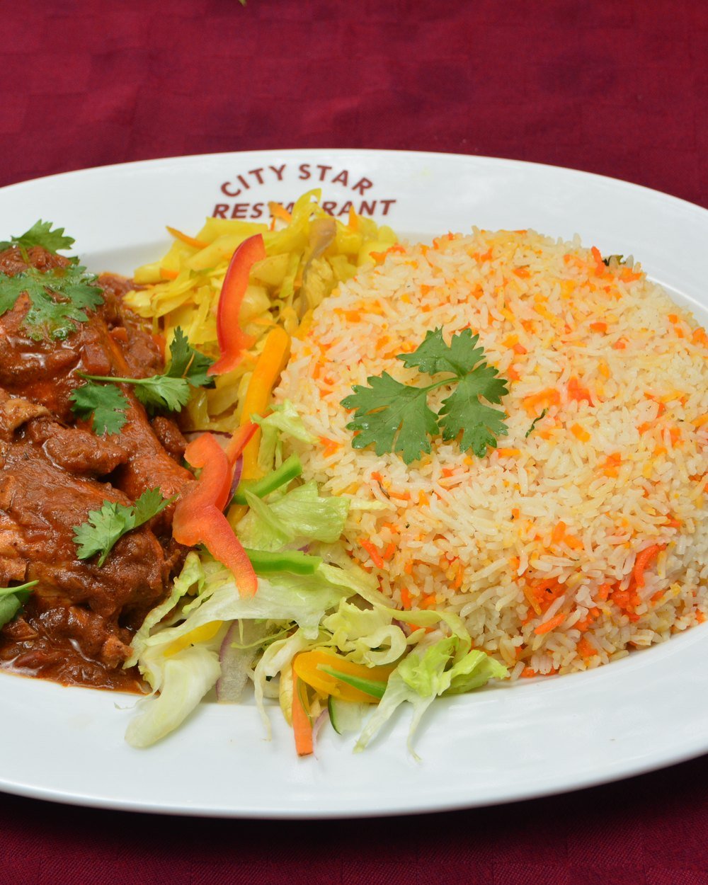 Goat stew with pilau and salad on a City Star Restaurant plate